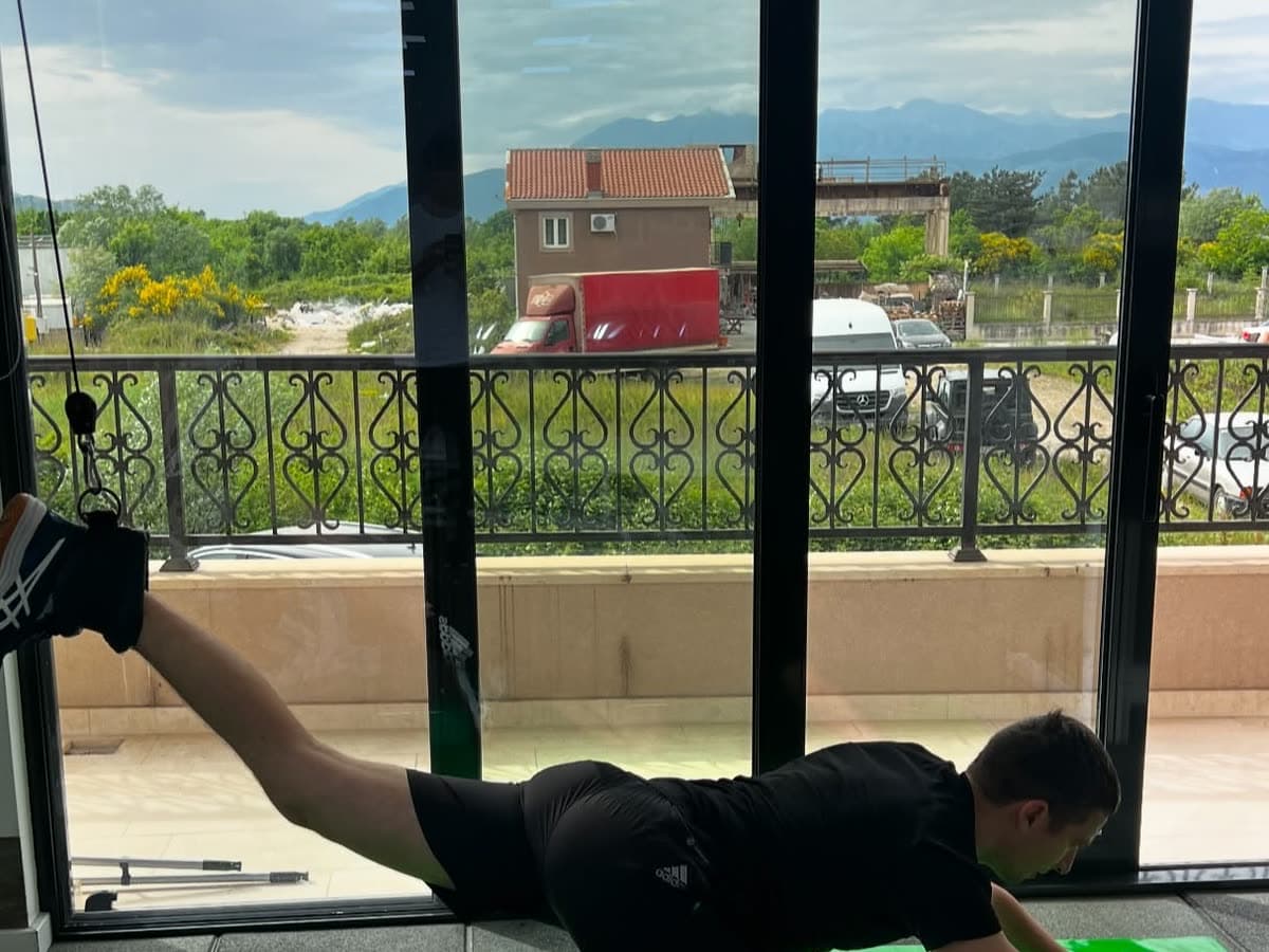A patient holding a plank on a mat in front of the clinic windows