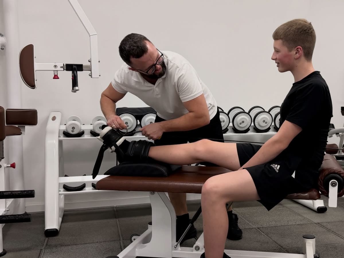 A therapist loading a patient’s knee on a leg machine