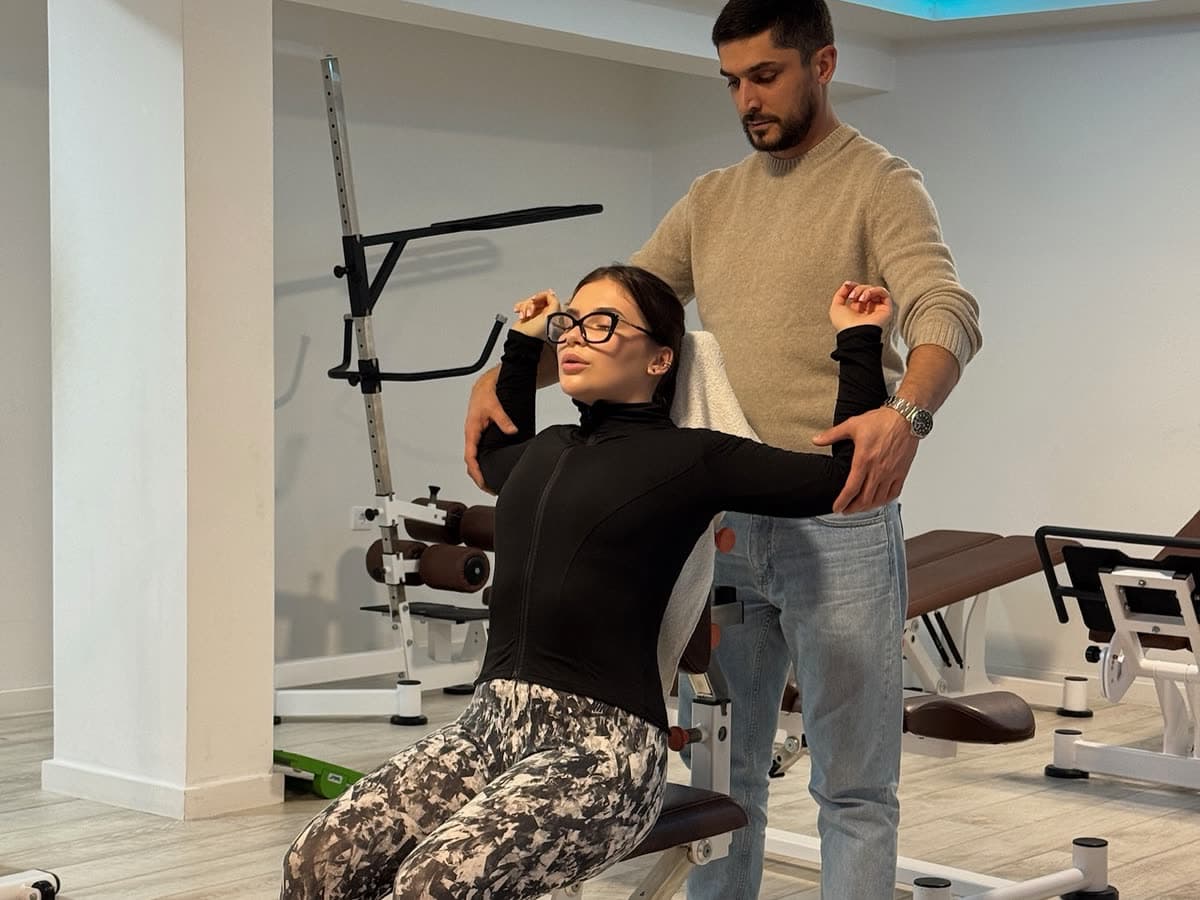 A therapist supporting a seated patient through a shoulder press